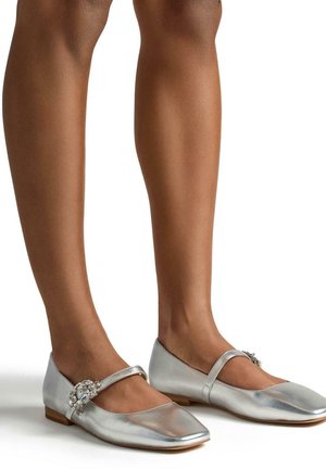 Zilveren metallic platte schoenen met een spitse neus, voorzien van een smalle band en versierde bloemdetails aan de zijkant. Gladde textuur.