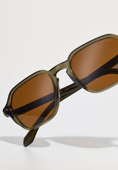 Brown tinted sunglasses with an olive green transparent frame. Rectangular shape with thick arms, featuring subtle branding on the interior.