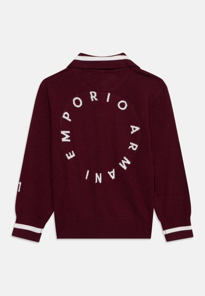 Pull rouge foncé à manches longues avec des rayures blanches sur les poignets et le col, avec le nom de la marque "Emporio Armani" dans un motif circulaire au dos.