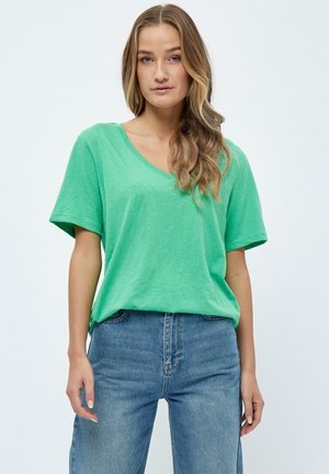 T-shirt verde a scollo a V realizzata in materiale morbido con maniche corte, abbinata a jeans blu a vita alta. Design semplice, senza motivi o dettagli.