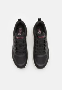 Scarpe da ginnastica nere con tomaia in mesh testurizzato, design con lacci, colletto imbottito e suola in gomma. Presentano accenti rosa con logo sulla linguetta.