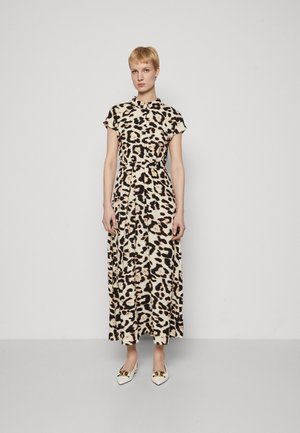 Maxi dress in beige with black and brown leopard print, short sleeves, cinched waist, and flowy fabric. Worn with white pointed shoes featuring gold accents.