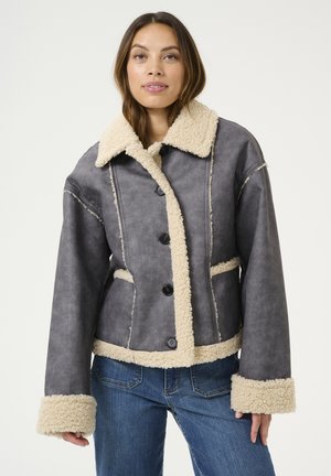 Grijs faux scheerwoljack met een beige kraag en manchetten, voorzien van een knopenfront en zijzakken. Zachte textuur, cropped ontwerp.