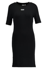 Abito corto nero a maniche corte realizzato in morbido cotone, caratterizzato da un colletto girocollo e spacco laterale. Piccolo logo Adidas posizionato sul petto.