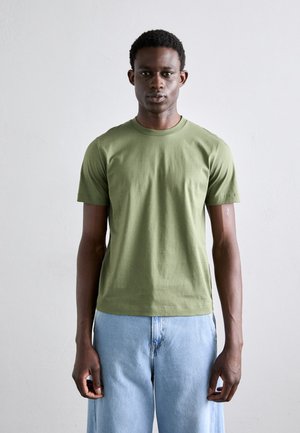 Olive green, short-sleeve t-shirt in a soft, smooth fabric, paired with light blue loose-fitting jeans. Simple design with crew neck.