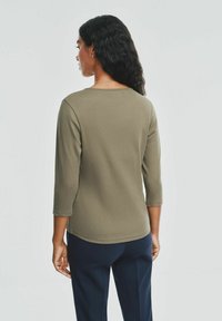 Oliwkowy, długi rękaw top z okrągłym dekoltem i prążkowaną teksturą, w połączeniu z granatowymi spodniami, widok z tyłu.