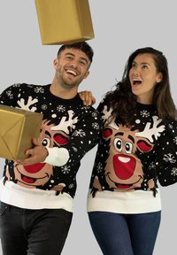 Schwarze Strickpullover mit weißen Schneeflocken und einem großen Rentierdesign. Die Männer und Frauen lächeln und halten goldene Geschenkkartons.