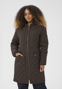 Manteau long matelassé marron avec une fermeture éclair dorée, un col côtelé et des poches latérales. Présente un motif en diamant et une texture lisse.