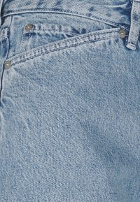 Ljust blå denimjeans med en urvuxen struktur, femficksdesign, metallbeslag och kontrasterande sömdetaljer.
