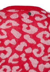 Maglione rosso lavorato a maglia con un motivo a stampa leopardata bianca, dalla texture che appare morbida e soffice. Include un piccolo logo nero sul retro.