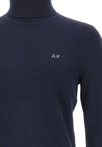 Maglione a collo alto in maglia tessuta blu navy con triangolo bianco e "X" ricamati sul petto sinistro.