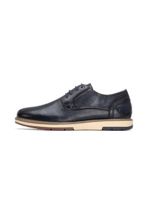 Zapato de cuero azul marino con un acabado liso, punta redonda y diseño de cordones. Presenta una suela contrastante en beige y rojo con un sutil detalle de logotipo.