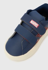 Tumesinised vabaajajalatsid kahe takjapaelaga, valge tallaga ja punase Marveli logoga. Küljel on tekstureeritud disain võrgumustriga.