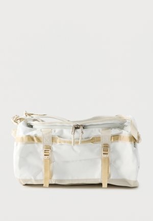 Biała prostokątna torba podróżna z beżowymi paskami, dwoma klamrami, zamkiem błyskawicznym z podwójnym suwakiem oraz regulowanym paskiem na ramię.