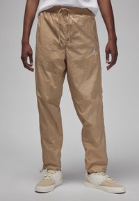 Beiga lätta joggerbyxor med elastisk midja, dragsko och broderad logotyp på vänster lår. Slät, texturerad tyg.