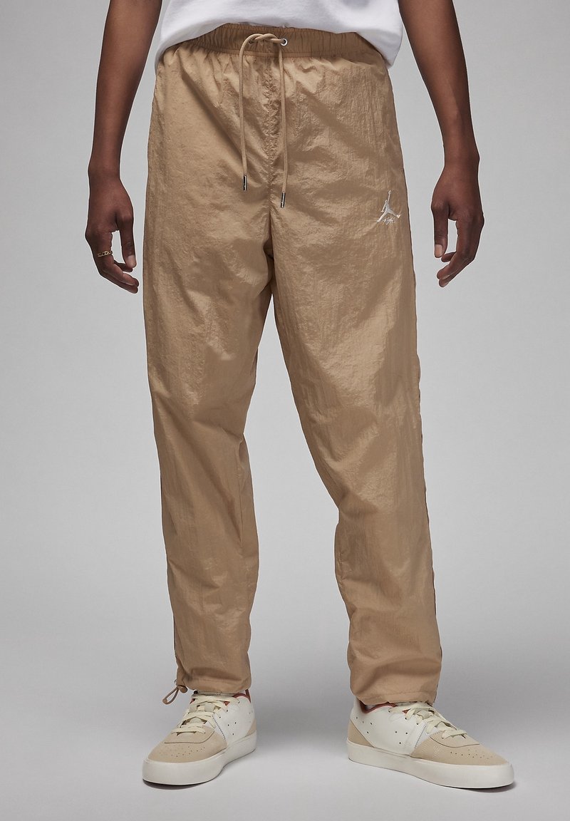 Beiga lätta joggerbyxor med elastisk midja, dragsko och broderad logotyp på vänster lår. Slät, texturerad tyg.