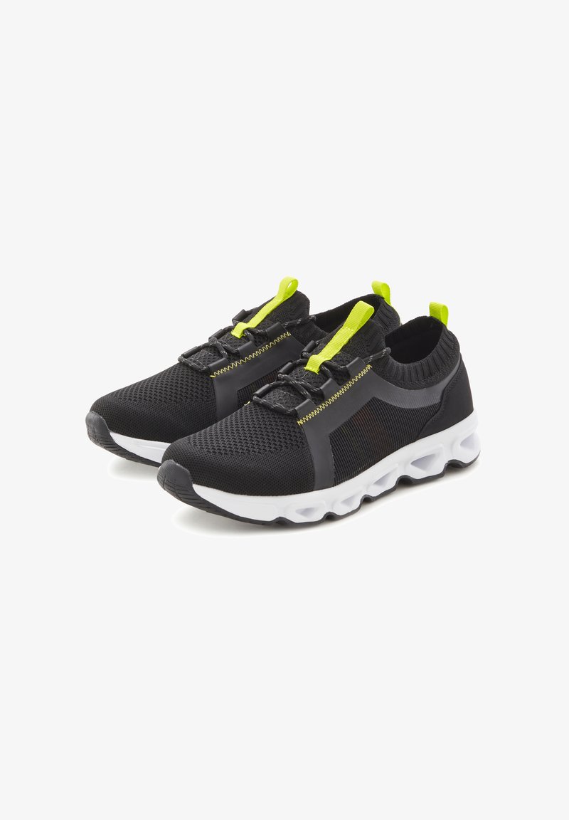 Black athletic shoes with a mesh upper, featuring bright yellow accents and elastic laces, complemented by a white, chunky sole.