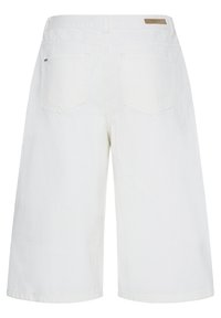Shorts en denim blanc jusqu'aux genoux avec des poches arrière et une petite étiquette de marque marron sur la ceinture.