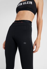 Leggings neri con un alto punto vita, con logo Calvin Klein sulla coscia e nome del marchio in contrasto sull'elastico in vita. Tessuto elasticizzato.