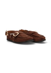 Zapatos de ante marrón tipo slip-on con punta redondeada, correa decorativa y acentos de hardware en tono dorado en los laterales. Suela de goma negra.
