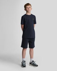 T-shirt en coton navy à manches courtes et encolure ronde, associé à un short navy. Agrémenté d'un petit logo jaune. Chaussures de sport portées.