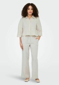 Chemise à boutons gris clair, texturée, à manches courtes, associée à un pantalon ample à taille élastique assorti. Design simple dans l'ensemble.