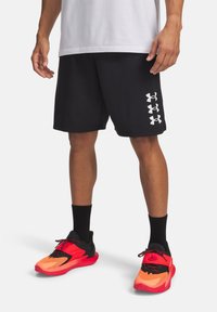 Μαύρα αθλητικά σορτς με υφή και τρία λευκά λογότυπα Under Armour στην αριστερή πλευρά, σε συνδυασμό με ζωντανά πορτοκαλί και μαύρα αθλητικά παπούτσια.