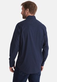 Navyblaues Hemd mit Knöpfen, das kleine weiße und rote geometrische Muster aufweist, lange Ärmel und einen klassischen Kragen hat. Taillierte Passform mit abgerundetem Saum.