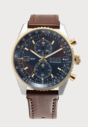 Zegarek chronograf z czarną tarczą, złotymi akcentami, okienkiem daty, dwoma subtarczami, brązowym skórzanym paskiem i oznaczeniem BOSS Skytraveller.