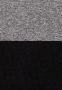 Tessuto lavorato a maglia in grigio e nero; presenta due sezioni orizzontali, con una parte superiore grigia texture sopra una parte inferiore nera liscia.