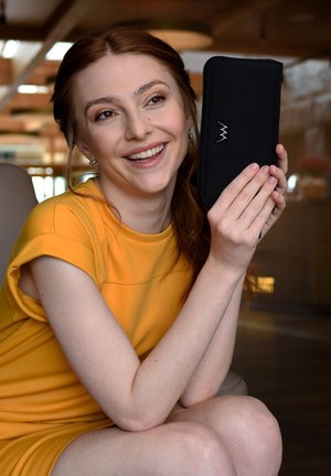 Black fabric wallet with a sleek design, featuring a silver lightning bolt logo. Background includes soft lighting and wooden elements.