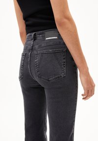 Zwarte spijkerbroek met hoge taille, met een gladde textuur, twee achterzakken en een merklabel op de tailleband.