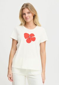 Camiseta de algodón crema con un diseño gráfico de flor roja en el centro, mangas cortas y cuello redondo. Tela suave y ligera.