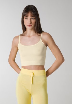 Top sin mangas amarillo cortado con tirantes finos, hecho de tela acanalada. Combinado con leggings amarillos a juego que cuentan con una cintura con cordón.