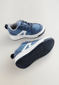 Niebieskie buty sportowe z siateczkowej i syntetycznej cholewki, kontrastującymi białymi akcentami, wyściełanym kołnierzem i teksturowaną czarną gumową podeszwą.