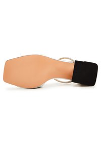 Sandalo con tacco a blocco nero e suola color nocciola, caratterizzato da una fibbia metallica e tessuto texture sul tallone. Superficie liscia con elementi di design minimi.