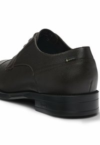 Scarpa in pelle marrone con finitura texturizzata, design con lacci e suola nera con un logo discreto. Include un accento in Gore-Tex per la resistenza all'acqua.