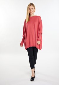 Pulover corai lejer, dintr-un material moale, cu mâneci lungi, asociat cu pantaloni negri până la glezne și pantofi negri cu toc.