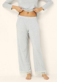 Lichtgrijze loungewear-broek met een ontspannen pasvorm, kantaccenten aan de zoom en een zachte stoftextuur, gecombineerd met een bijpassend langslavend top.