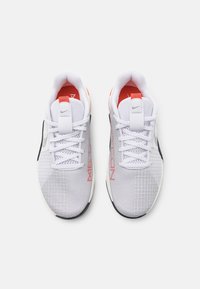 Scarpe da ginnastica bianche con tomaia in rete, dotate di accenti rossi, lacci a bloccaggio e pannelli grigi a fantasia sui lati. Suola in gomma nera.