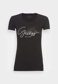 Czarny, dopasowany T-shirt z krótkim rękawem, okrągłym dekoltem i połyskującymlogo "Guess EST. 1981" na piersi.