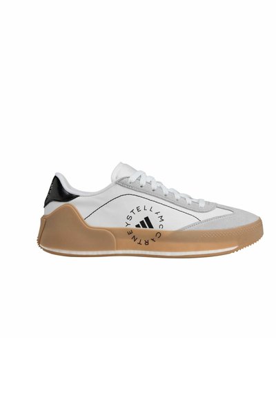White athletic shoe with a grey suede toe, black heel cap, white laces, and a tan rubber sole. Features logo on the side.