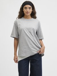 Šedé bavlněné tričko s uvolněným střihem, s síťovaným detailem na spodním lemu a ohrnutými krátkými rukávy, spárované s tmavě modrými kalhotami s širokými nohavicemi.