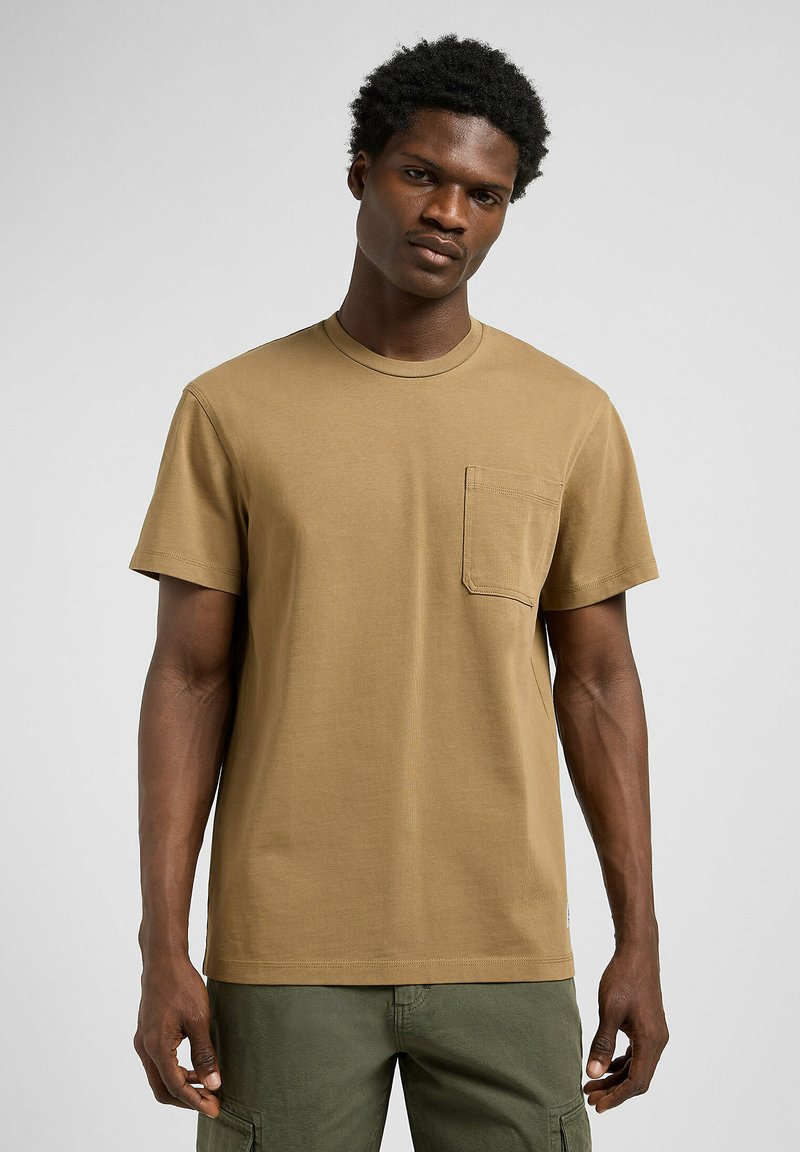 T-shirt di cotone color khaki con scollatura rotonda, maniche corte e una tasca sul petto. Tessuto morbido, vestibilità comoda e design semplice.