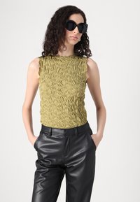 Stickad linne i olivgrön med texturerat blommönster, kombinerat med svarta läderbyxor, med avslappnad passform och sidofickor.