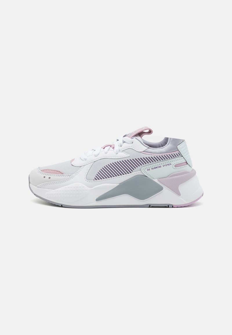 Zapatillas con una parte superior de malla blanca, acentos en gris y púrpura pastel, y una suela texturizada. Presenta rayas pronunciadas y un cuello acolchado.