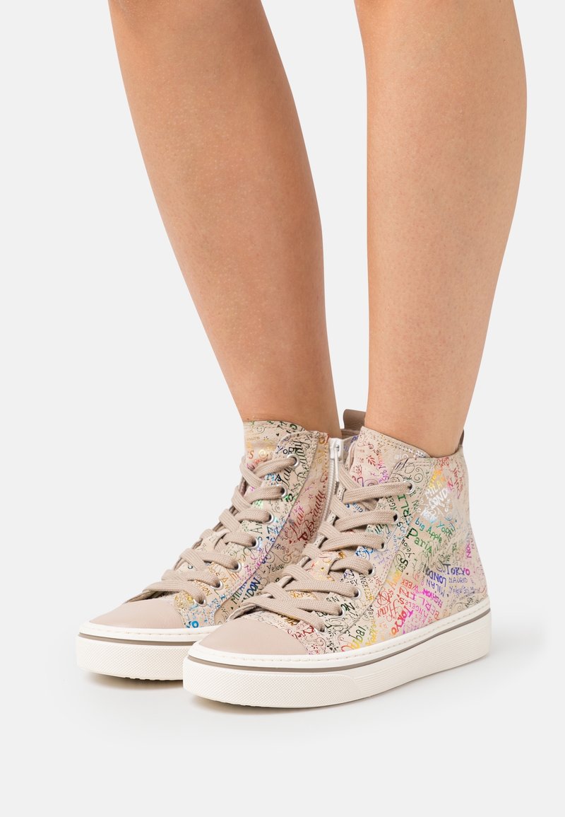 Baskets montantes en toile beige avec des motifs de texte multicolores, dotées d'une semelle en caoutchouc blanche et d'une fermeture éclair latérale.