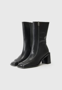 Sorte lær ankle boots med firkantet tå, blokkhæl og kontrastsøm; har en sidelukking for enkel påkledning.
