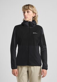 Giacca outdoor nera con zip frontale, cappuccio, maniche lunghe e dettaglio logo. Realizzata in un materiale leggero e liscio con texture a contrasto.