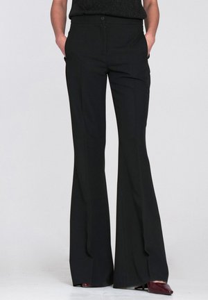 Czarne spodnie z rozszerzanymi nogawkami wykonane z gładkiej tkaniny. Posiadają płaski przód, boczne kieszenie oraz zapięcie na guzik w pasie.